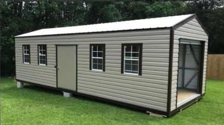 Single-story portable storage shed with gray vinyl siding and white trim